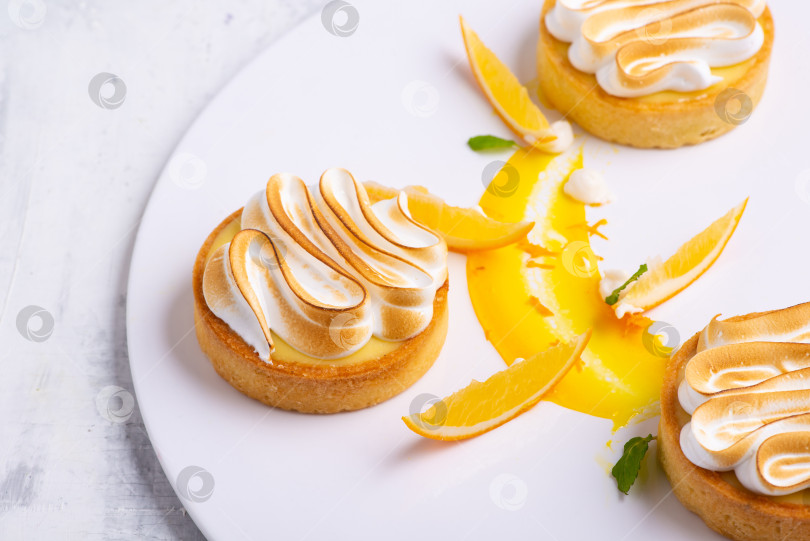 Скачать Аппетитные лимонные тарталетки с безе подаются на белой тарелке фотосток Ozero