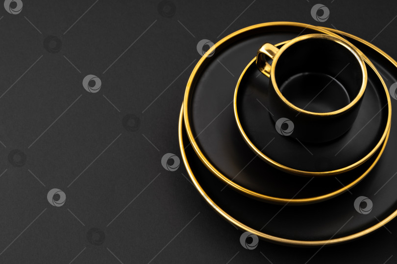 Скачать Набор черных и золотистых керамических тарелок и чашек на черной подставке фотосток Ozero
