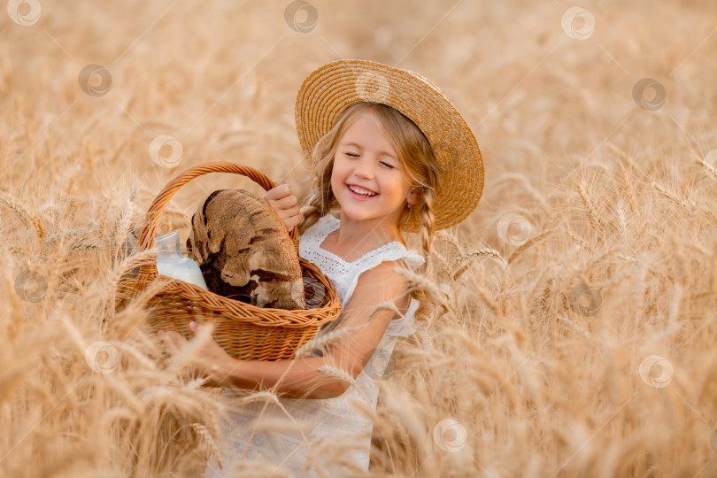 Скачать Маленькая светловолосая девочка держит корзинку с хлебом на пшеничном поле. экологически чистые фермерские продукты. сбор урожая пшеницы фотосток Ozero