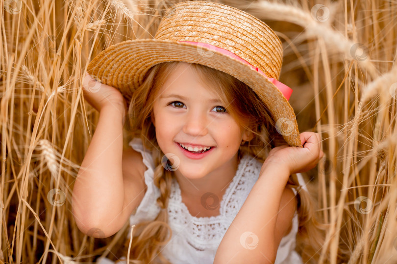 Скачать Очаровательная маленькая девочка играет на пшеничном поле теплым летним днем фотосток Ozero