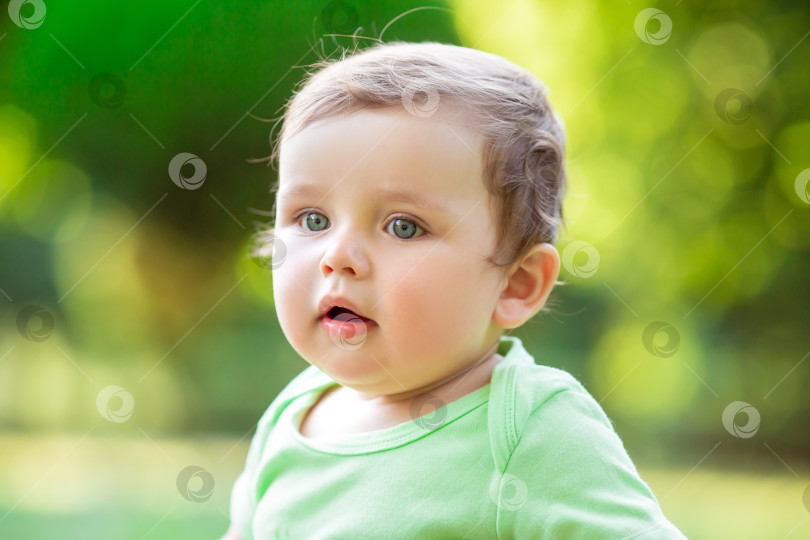 Скачать Симпатичный малыш в зеленом боди летом сидит на траве и играет с развивающими игрушками. Малыш грызет силиконовые кубики. Развитие ребенка до одного года фотосток Ozero