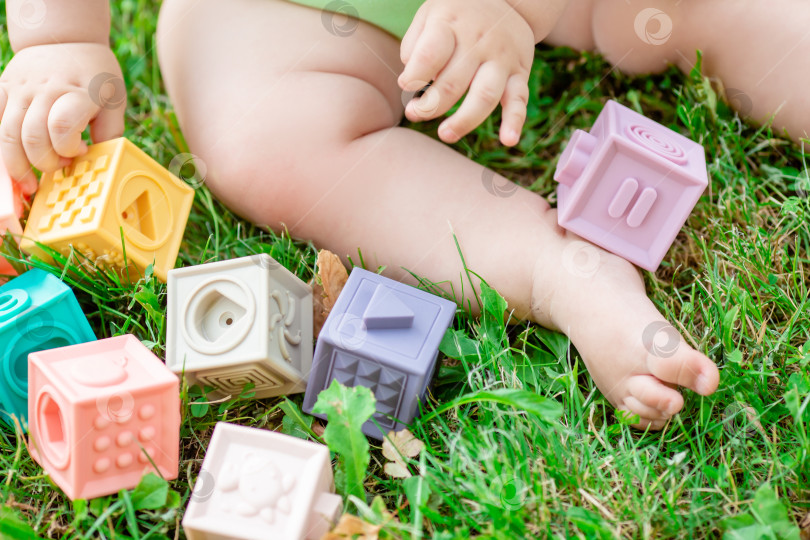 Скачать детские ножки и ручки с силиконовыми кубиками на траве, крупным планом. развивающие игрушки для детей фотосток Ozero