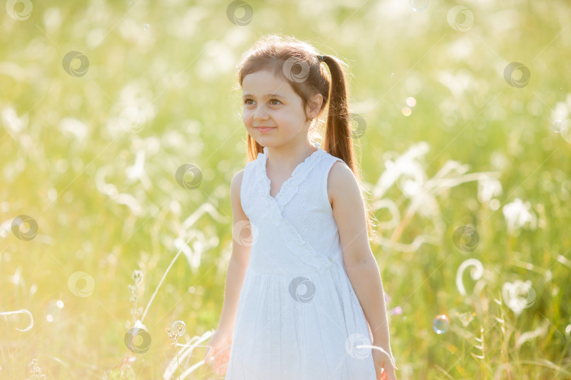 Скачать Маленькая девочка надувает мыльные пузыри летом на прогулке фотосток Ozero