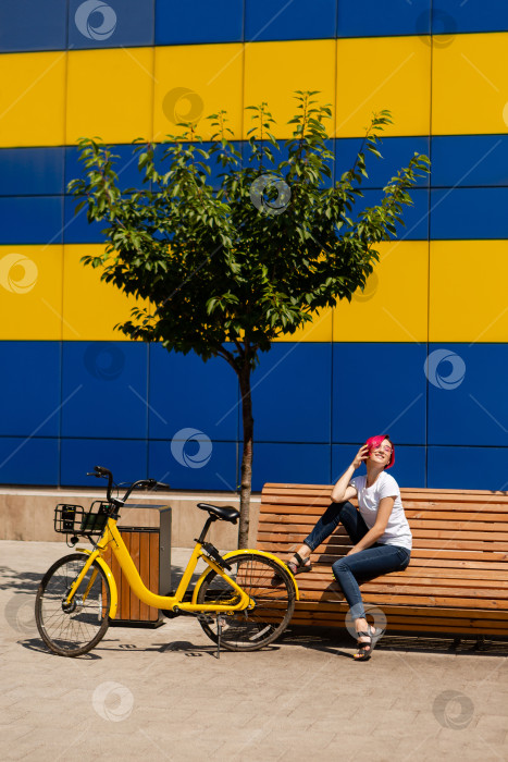 Скачать Счастливая молодая женщина с розовыми волосами летом прогуливается по городу на велосипеде. Экологичный вид транспорта фотосток Ozero