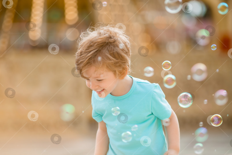 Скачать Счастливый мальчик играет с мыльными пузырями в летнем парке развлечений. Образ жизни детей фотосток Ozero