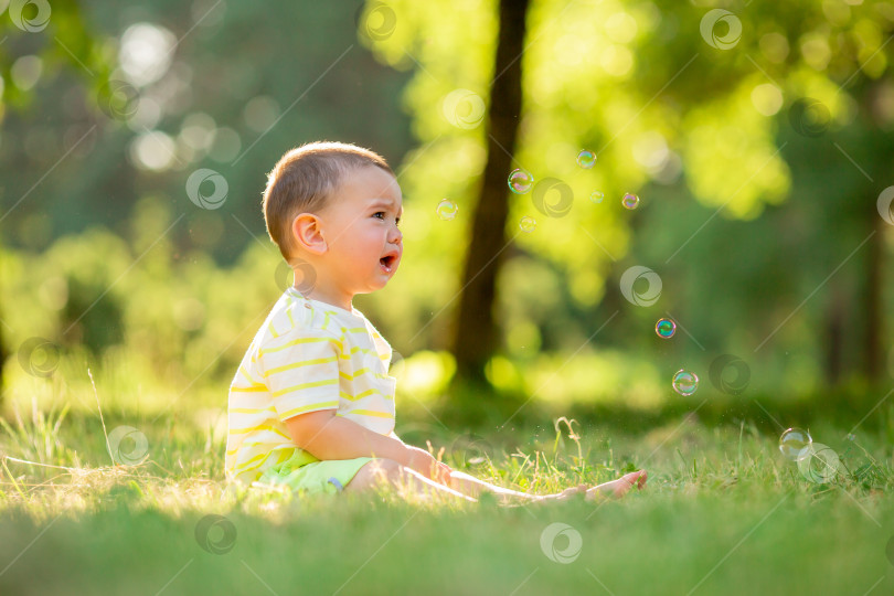 Скачать Счастливый малыш сидит летом на зеленой траве в парке. Образ жизни детей фотосток Ozero