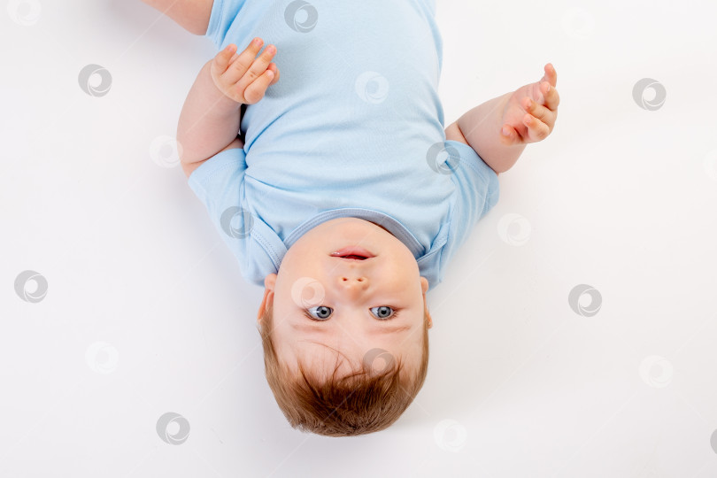 Скачать Симпатичный мальчик-карапуз 8 месяцев от роду в синем боди сидит на белом фоне, место для текста фотосток Ozero