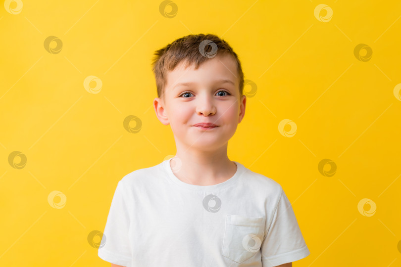 Скачать Счастливый мальчик 7 лет в белой футболке на желтом фоне фотосток Ozero