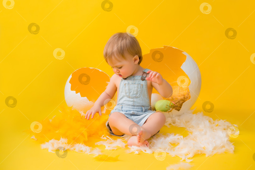 Скачать малышка сидит с декоративными пасхальными яйцами на желтом фоне. концепция Пасхи фотосток Ozero