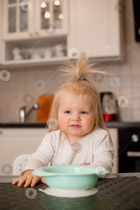 Скачать Симпатичная маленькая блондинка ест на кухне своего дома фотосток Ozero