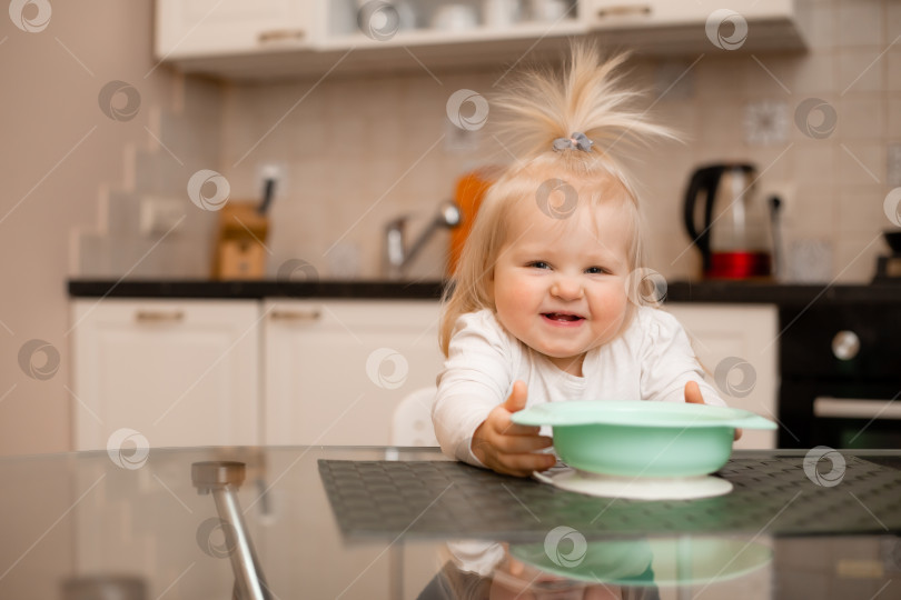 Скачать Симпатичная маленькая блондинка ест на кухне своего дома фотосток Ozero