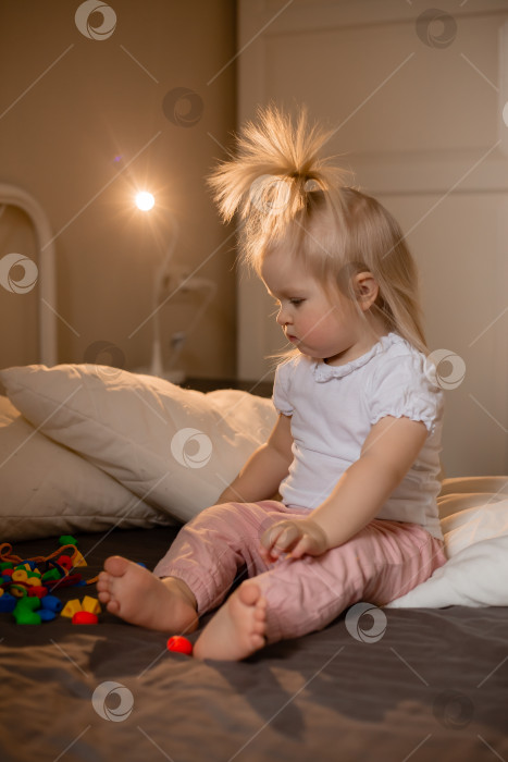 Скачать Маленькая девочка лежит дома в постели. Счастливый ребенок дома фотосток Ozero
