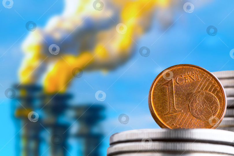 Скачать Монета достоинством в один евроцент с изображением денег на фоне промышленных фабричных труб. фотосток Ozero
