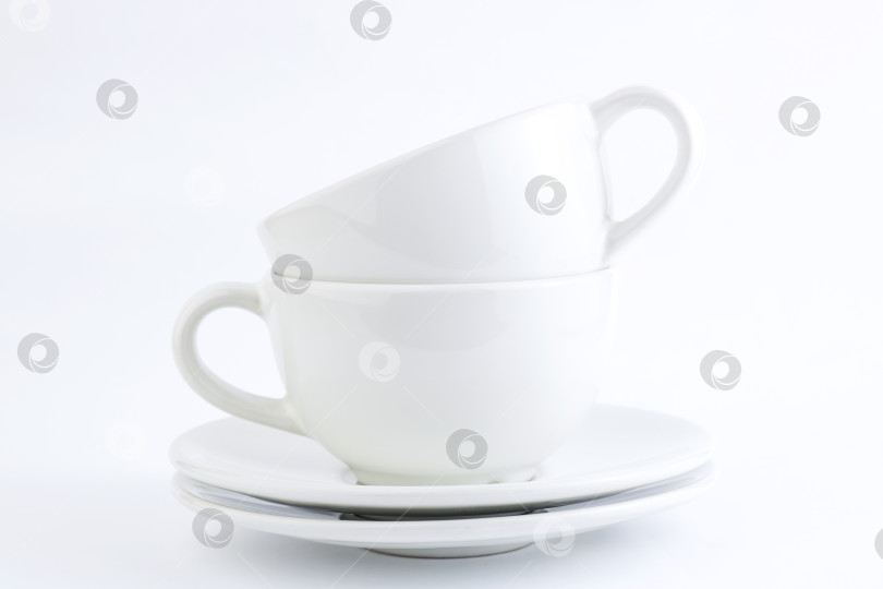 Скачать Белые чашки и блюдца, расставленные стопкой на белом фоне. Пространство для копирования фотосток Ozero