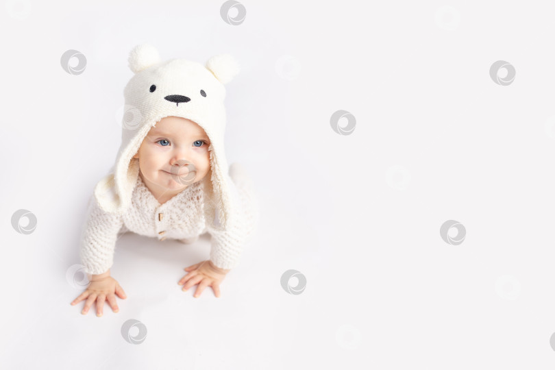 Скачать ребенок ползает в теплом костюме и шапочке на белом изолированном фоне, место для текста фотосток Ozero