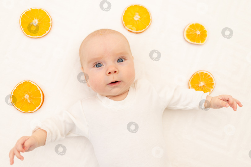 Скачать Портрет младенца на белом фоне с апельсинами. Постельное белье для детей. 8 месяцев. Здоровый ребенок в боди-пижаме. Аллергия на цитрусовые у детей фотосток Ozero