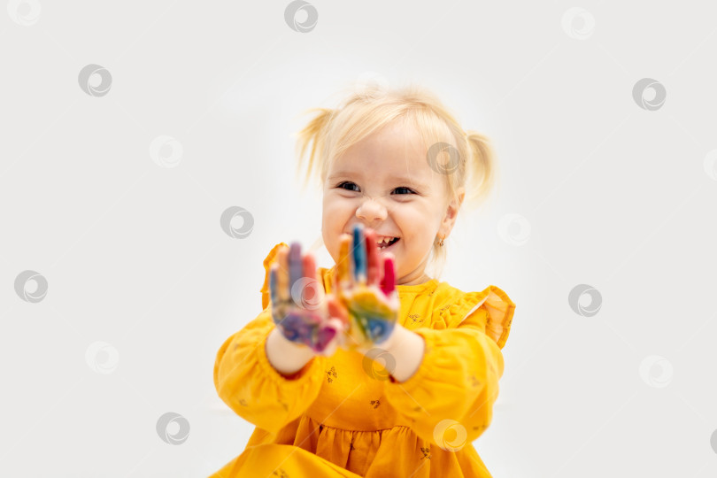 Скачать маленькая девочка с раскрашенными руками, перепачканными краской, в желтой одежде рисовала на белом изолированном фоне фотосток Ozero