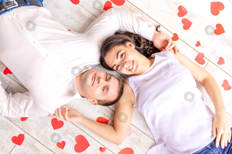 Скачать день святого Валентина, влюбленная пара лежит среди сердец на полу, обнимаясь фотосток Ozero