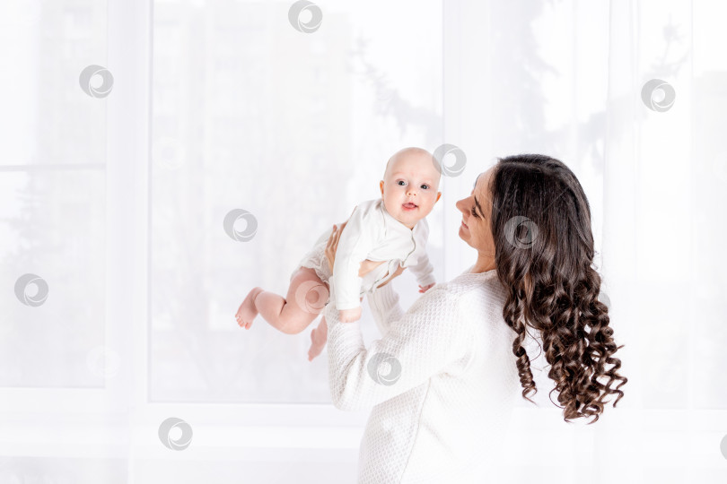 Скачать красивая мать с ребенком на руках у окна дома, концепция счастливой любящей семьи, стиль жизни фотосток Ozero