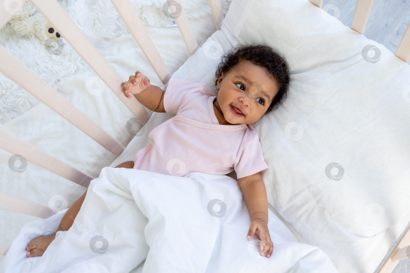 Скачать афроамериканский мальчик в кроватке ложится спать или просыпается утром и улыбается в спальне фотосток Ozero