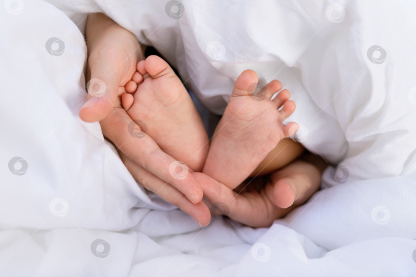 Скачать руки кавказской мамы, держащей маленькие ножки своего ребенка, чернокожего африканского младенца фотосток Ozero