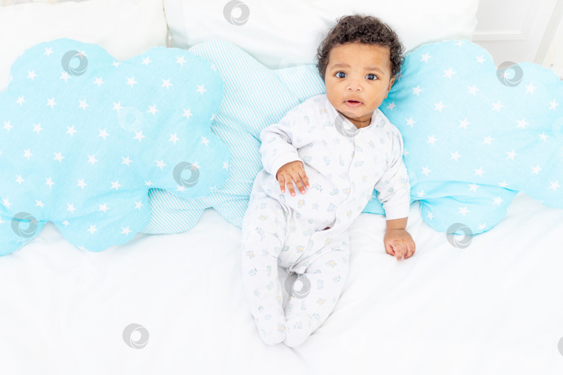 Скачать Маленький афроамериканец лежит в пижаме на белой кровати в спальне фотосток Ozero