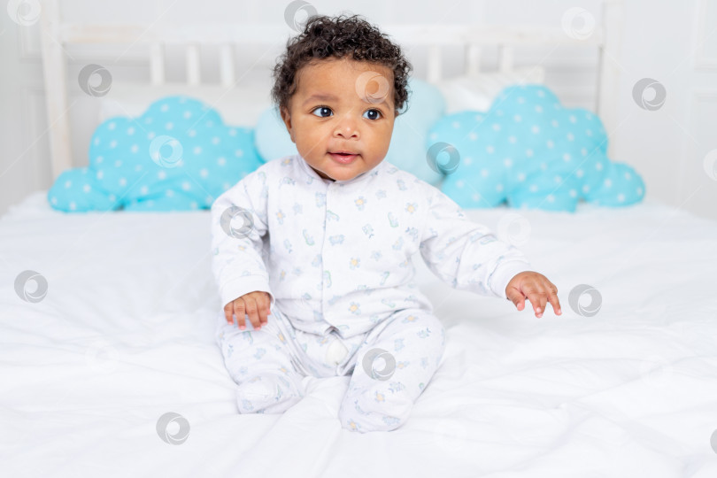 Скачать Маленький афроамериканец лежит в пижаме на белой кровати в спальне фотосток Ozero