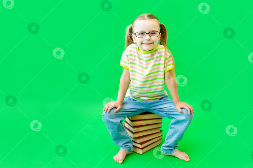 Скачать девочка, сидящая на зеленом фоне над книгами в очках, место для текста фотосток Ozero