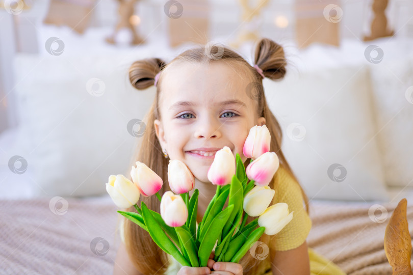 Скачать портрет милого ребенка крупным планом с весенними цветами - розовыми тюльпанами, улыбающегося и радующегося или дающего в качестве подарка на женский день или день матери фотосток Ozero
