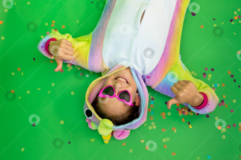 Скачать маленькие девочки в ярких костюмах лежат на зеленом изолированном фоне с серпантином в ярких костюмах единорогов. Место для текста. Концепция праздника, Дня рождения и распродаж фотосток Ozero
