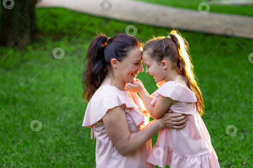 Скачать мать и дочь 5-6 лет сидят летом в парке на траве и смеются, разговор матери и дочери, концепция счастливой семьи, отношения матери и ребенка, День матери фотосток Ozero