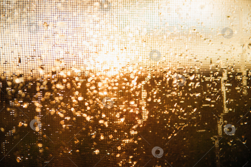 Крупный план капель дождя на прозрачном стекле.Размытый фон силуэтного пейзажа, солнце с золотистым светом во время заката или восхода солнца.Текстура мокрого стекла. Абстрактный фон. - Ozero - российский фотосток