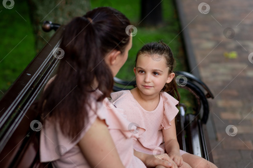 Скачать мать и дочь 5-6 лет гуляют летом в парке, мать разговаривает с дочерью, сидя на скамейке, концепция счастливой семьи, отношения матери и ребенка, день матери фотосток Ozero