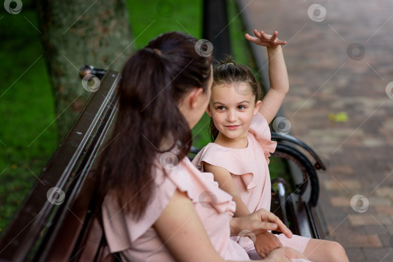Скачать мать и дочь 5-6 лет гуляют летом в парке, мать разговаривает с дочерью, сидя на скамейке, концепция счастливой семьи, отношения матери и ребенка, день матери фотосток Ozero