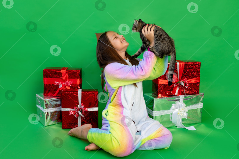 Скачать милая маленькая девочка на зеленом фоне в ярком костюме получила кошку в подарок на день рождения. Место для текста. Концепция Нового года и Рождества, животное в подарок фотосток Ozero