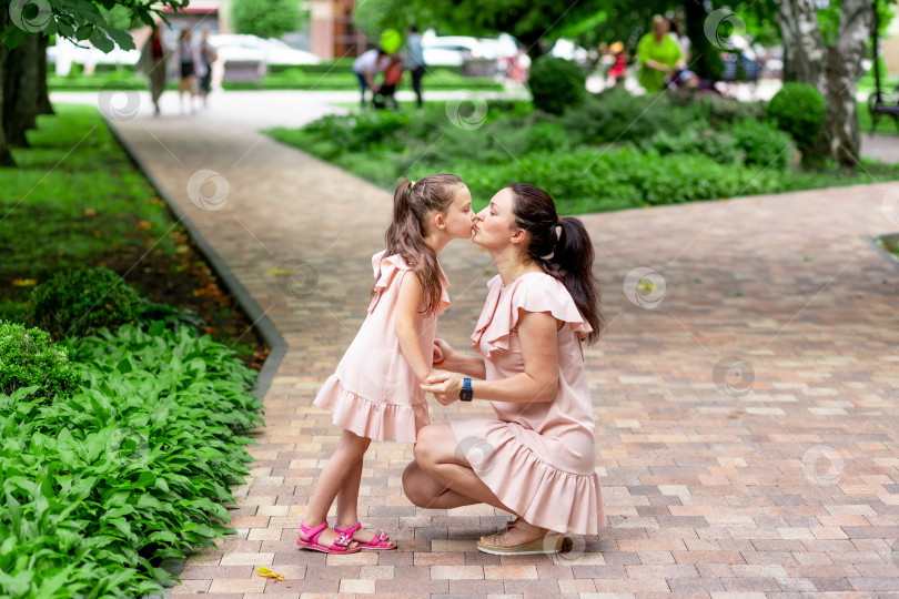 Скачать Счастливые мать и дочь 5-6 лет гуляют летом в парке, мать целует свою дочь, концепция счастливой семьи, отношения матери и ребенка фотосток Ozero