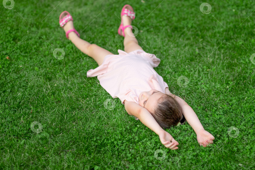 Скачать девочка 5-6 лет лежит на спине в парке на траве, счастливое детство, день защиты детей фотосток Ozero