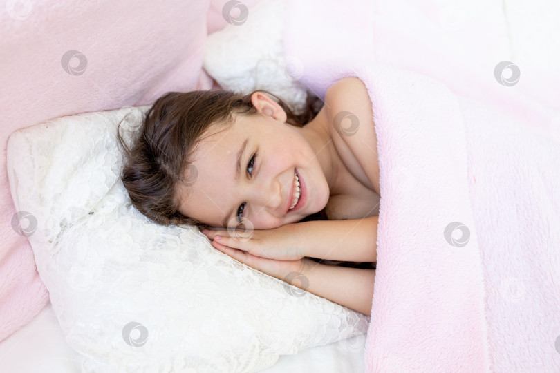 Скачать маленькая девочка 5-6 лет улыбается во сне, ребенок лежит в постели, сложив руки под головой фотосток Ozero