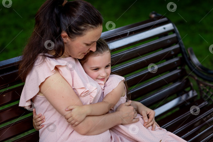 Скачать мать и дочь 5-6 лет гуляют летом в парке, мать обнимает дочь, сидя на скамейке, концепция счастливой семьи, отношения матери и ребенка, день матери фотосток Ozero