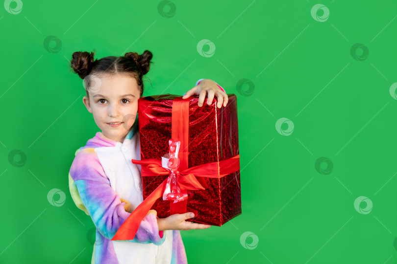 Скачать милая маленькая девочка на зеленом фоне в ярком костюме и шляпе, держащая подарок. Место для текста. Концепция Нового года и Рождества фотосток Ozero
