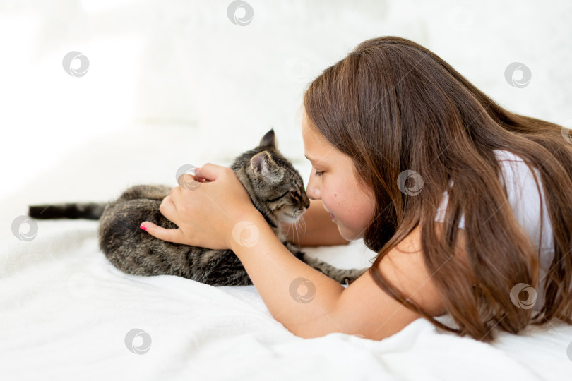 Скачать Ребенок мучает животное, маленькая девочка с кошкой лежат на кровати, концепция детской дружбы с животными фотосток Ozero