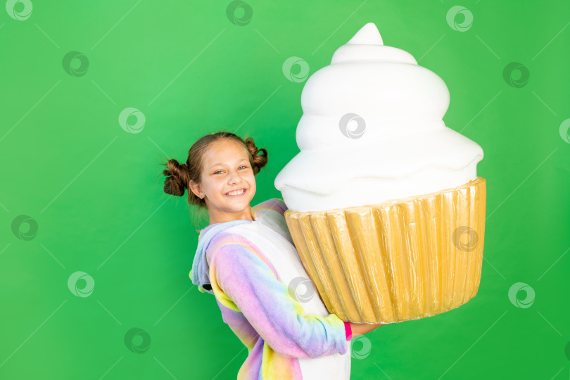 Скачать маленькая девочка на зеленом фоне в ярком костюме держит в руках огромный торт. Место для текста. Концепция нездоровой пищи и похудения фотосток Ozero