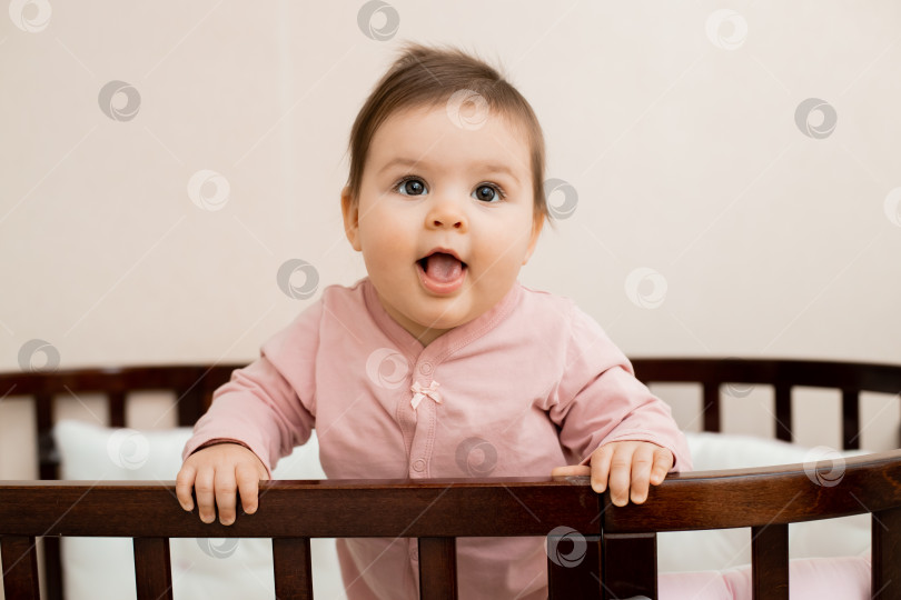 Скачать Портрет маленькой девочки, сидящей дома в детской кроватке в пижаме фотосток Ozero