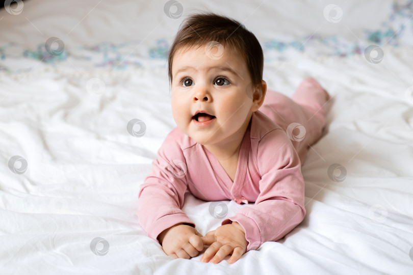 Скачать портрет улыбающейся маленькой девочки, лежащей на кровати с плюшевым мишкой. пробел для текста фотосток Ozero