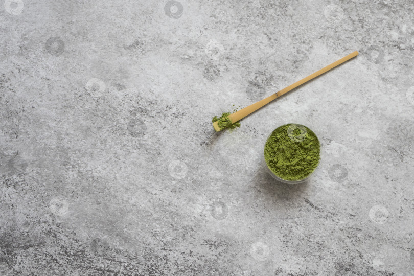 Скачать Чай Матча в миске и бамбуковая ложка на сером бетонном фоне. Эта порошкообразная форма зеленого чая является суперпродуктом. Концепция японской чайной церемонии. Вид сверху, место для копирования, плоское расположение. фотосток Ozero