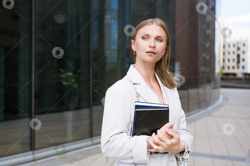 Скачать Успешная деловая женщина держит в руке блокнот перед офисным зданием. Хорошенький фотосток Ozero