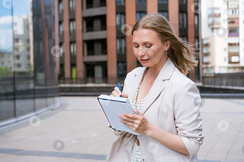 Скачать Деловая женщина в светлом жакете стоит и пишет что-то рядом с бизнесом фотосток Ozero