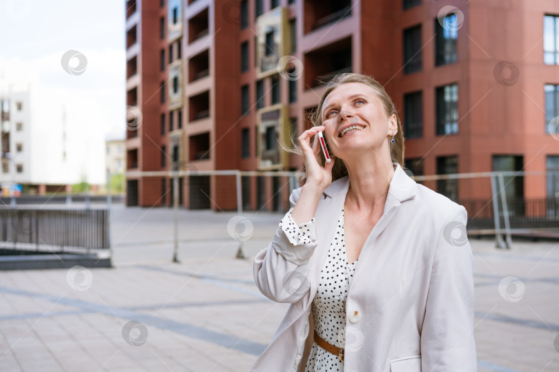 Скачать Успешная женщина разговаривает по телефону, идя по улице. фотосток Ozero