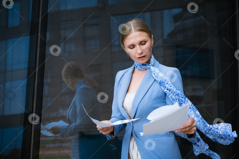 Скачать Деловая женщина держит в руке документы на фоне офисного здания фотосток Ozero