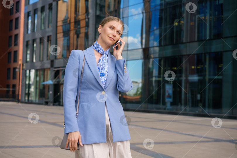 Скачать Стильная деловая женщина с телефоном в руке стоит в бизнес-центре фотосток Ozero
